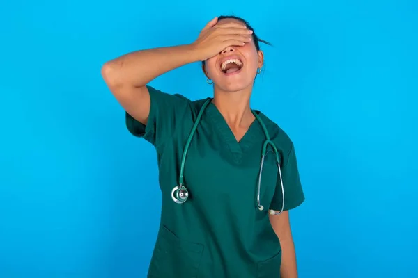 Hermosa Doctora Hispana Vistiendo Uniforme Médico Verde Sobre Fondo Azul — Foto de Stock