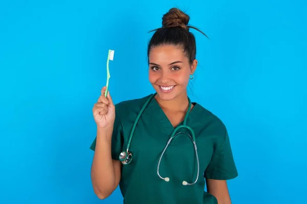 Die Schöne Hispanische Ärztin Grüner Arztuniform Vor Blauem Hintergrund Hält — Stockfoto