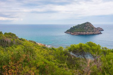 Kışın Tuscany, İtalya 'da Rocky kıyı şeridi ve su körfezi. Monte Argentario doğal parkı dramatik gökyüzü ormanı Akdeniz mavi suyu.
