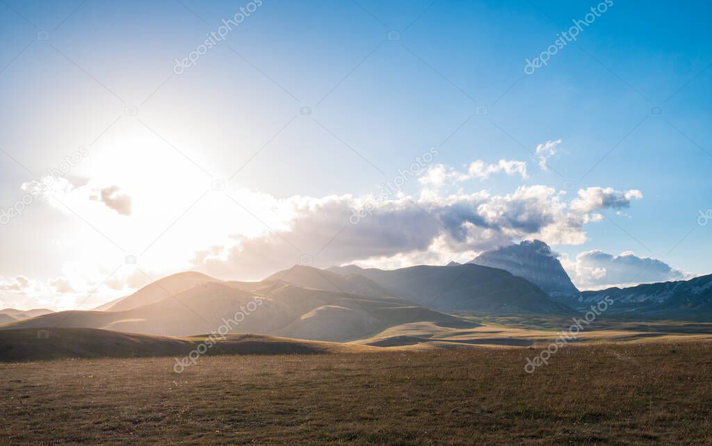 Sunset view point on rocky mountains, highlands and pastures. Campo Imperatore, Gran Sasso, Apennines, Italy. Colorful clouds in the sky on dramatic mountain ridge.