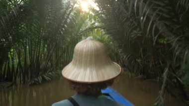 Mekong Nehri Delta Bölgesi, Ben Tre, Güney Vietnam 'da tekne turu. Vietnam şapkalı bir turist su kanallarında Hindistan cevizi palmiyeleri fidanlığında geziyor..