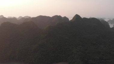 Hava: Güneş batarken Ha Long Körfezi ve Cat Ba adası üzerinde eşsiz bir uçuş, Vietnam 'da ünlü bir turizm merkezi. Bulutlu manzaralı gökyüzü, ufuktaki denizde kireçtaşı kaya zirveleri. yerel d-log sinemasıName