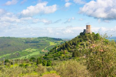 Rocca d 'Orcia, İtalya' nın Toskana şehrinde bir ortaçağ köyü ve kalesi. Taş kulenin eşsiz manzarası mavi gökyüzüne karşı kayalıklara tünemiş manzaralı bulutlarla..