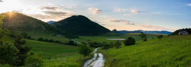 Montelago dağları üzerinde günbatımı dramatik gökyüzü, Marche, İtalya. Eşsiz tepe ve dağ yeşili manzara.