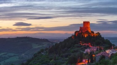 Rocca d 'Orcia, İtalya' nın Toskana şehrinde bir ortaçağ köyü ve kalesi. Alacakaranlıkta eşsiz bir manzara, taş kule dramatik gökyüzüne karşı kayalıklarda tünemişti..