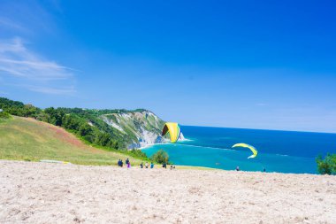 Portonovo, İtalya - 8 Mayıs 2022: Paragliderler Conero, İtalya 'nın doğal sahil şeridinden havalandılar. Akdeniz turizm beldesinde dramatik sahil burnu üzerinde aşırı spor