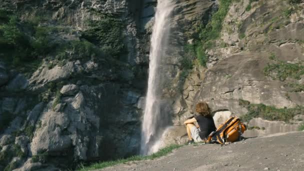 女性は山の上の滝を見て 風光明媚な高山の風景の中に屋外活動を行う一人 アルプスの夏休み フィットネスの幸福の自由 — ストック動画