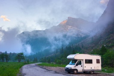Dağlarda, Alpler 'de, Piedmont' ta, İtalya 'da bir karavan. Günbatımı dramatik gökyüzü ve bulutlar, eşsiz dağlık araziler ve kayalık dağlar, alternatif vanlife tatil konsepti.