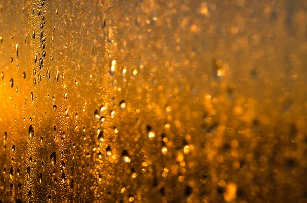 Wet yellow - gold glass background with drops and sparks — Stock Photo, Image
