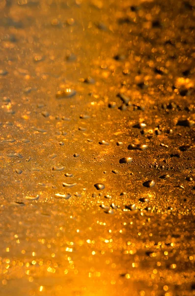 Giallo bagnato - sfondo in vetro dorato con gocce e scintille — Foto Stock