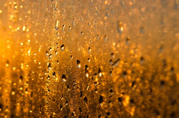 Wet yellow - gold glass background with drops and sparks — Stock Photo, Image