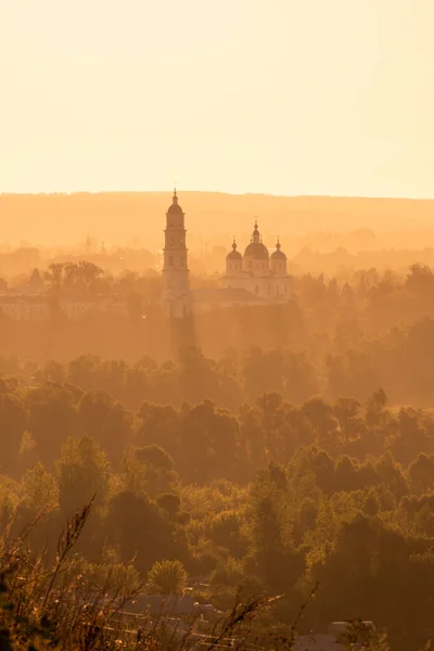 Russian Orthodox Church in the morning fog at dawn in the middle of the forest lit by golden light. High quality photo