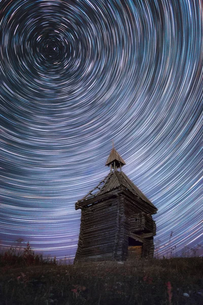 Circular Star Trails in night sky above old abandoned wooden chapel — Stok fotoğraf