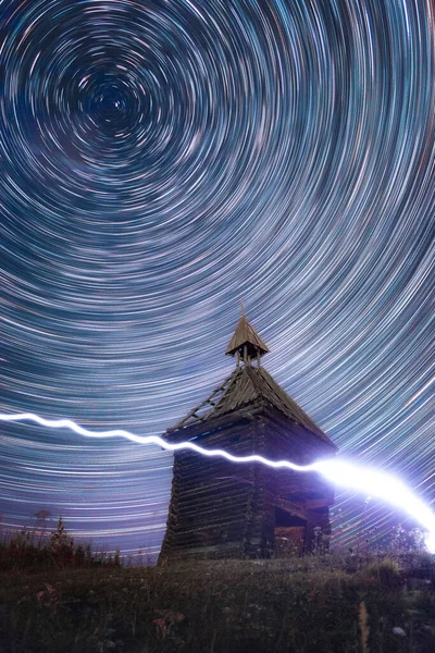 Circular Star Trails in night sky above old abandoned wooden chapel — стоковое фото