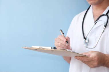 young doctor writing in clipboard on white table