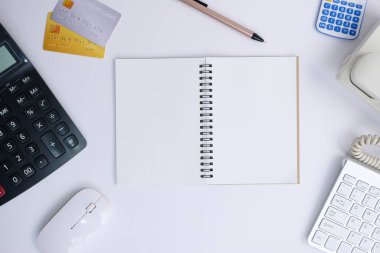 top view of office desk with calculator and notepad on white background