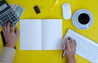 top view of keyboard, office supplies and notebook on yellow background