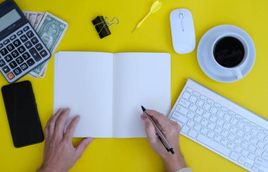top view of keyboard, office supplies and notebook on yellow background