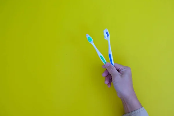 Closeup Shot Hands Holding Toothbrushes Yellow Background — Fotografia de Stock