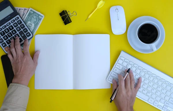 top view of keyboard, office supplies and notebook on yellow background