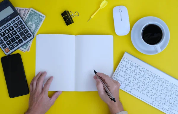 top view of keyboard, office supplies and notebook on yellow background