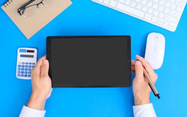 İş kadını masada dizüstü bilgisayar ve hesap makinesiyle çalışıyor.