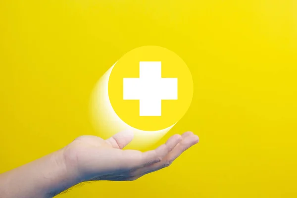 yellow medical cross with a plus sign on hand