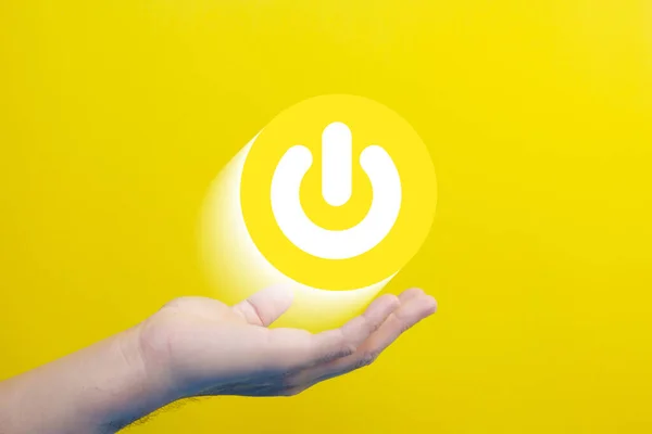 hand holding a yellow button with a symbol of power