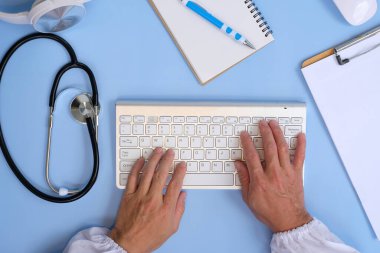 doctor writing notes and stethoscope on desk.