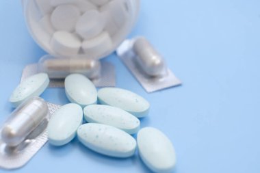 blue pills and capsules on blue background.