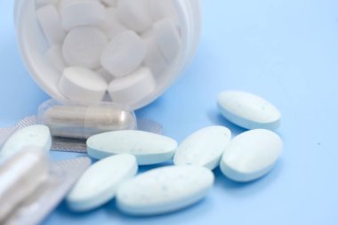 blue pills and capsules on blue background.