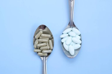 mavi arka planda kaşıkta haplar.