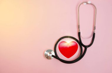 Pembe arka planda steteskop ve kırmızı kalp..