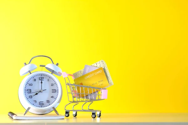 目覚まし時計付きショッピングカート黄色の背景にストップウォッチ オンラインで購入し配達するという概念は — ストック写真
