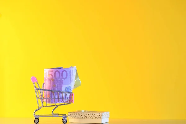 Gelber Warenkorb Mit Geld Auf Farbigem Hintergrund — Stockfoto