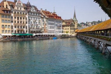 LUCERNE, SWitzERLAND, 21 Haziran 2022 - Reuss nehri üzerindeki Kapellbrucke Köprüsü ve İsviçre 'nin başkenti Lucerne' deki binaların manzarası