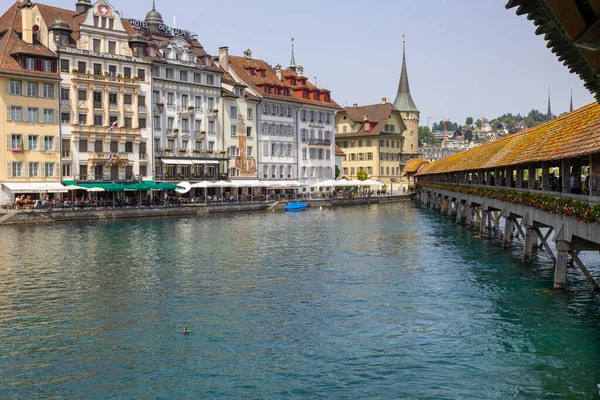 LUCERNE, SWitzERLAND, 21 Haziran 2022 - Reuss nehri üzerindeki Kapellbrucke Köprüsü ve İsviçre 'nin başkenti Lucerne' deki binaların manzarası