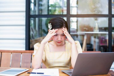 Young woman sitting in a cafe with her laptop, Stressful for work.	