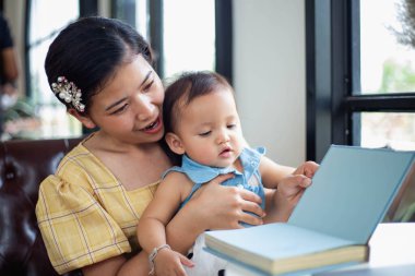 Anne ve kızı rahatlayın ve bir kitap okuyun.