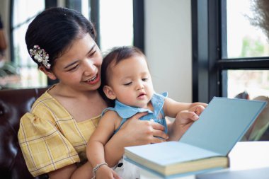 Anne ve kızı rahatlayın ve bir kitap okuyun.
