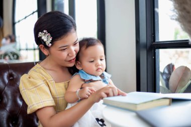 Anne ve kızı rahatlayın ve bir kitap okuyun.