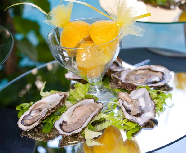 Oesters met citroenen op spiegel tafel — Stockfoto