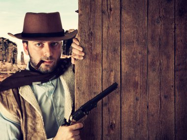 Bad gunman indicates with the gun a wooden plank clipart