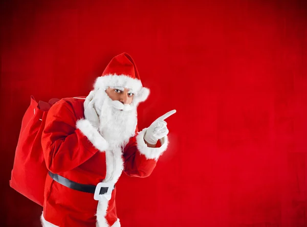 Santa Claus with sack pointing in blank red — Stock Photo, Image