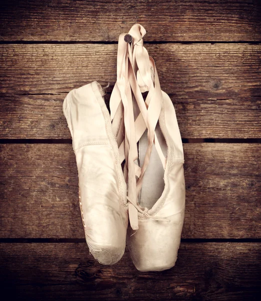 Used ballet shoes hanging on wooden background — Stock Photo, Image