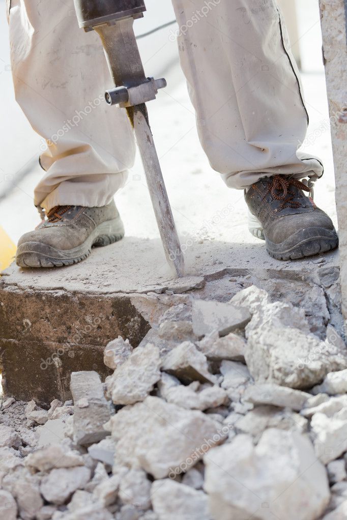 Worker demolishing the concrete with a jackhammer