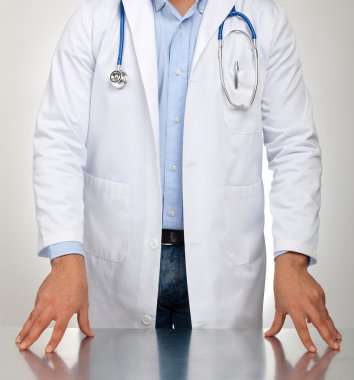 Doctor with hands resting on the table for examination clipart