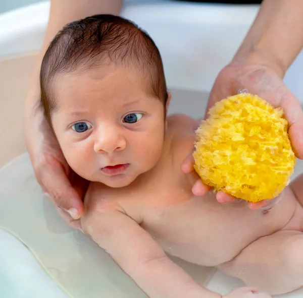 新生児の男の子の最初の風呂 お母さんは自然なスポンジで赤ちゃんを洗います — ストック写真