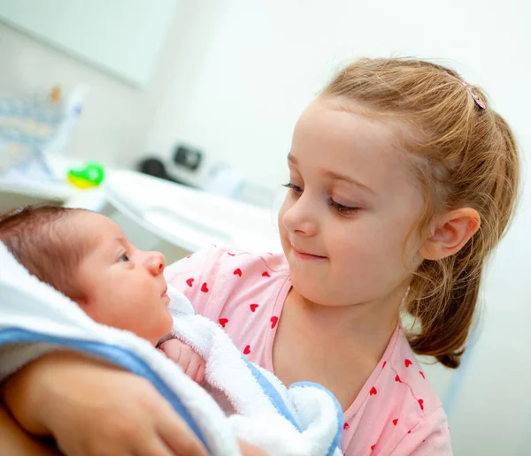 新生児の男の子の最初の風呂 赤ん坊は妹の腕の中のバスローブにいる — ストック写真