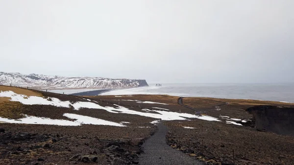 从冰岛的Dyrholaey灯塔眺望着冬季的黑色沙滩 那里下着雪 阳光明媚 — 图库照片